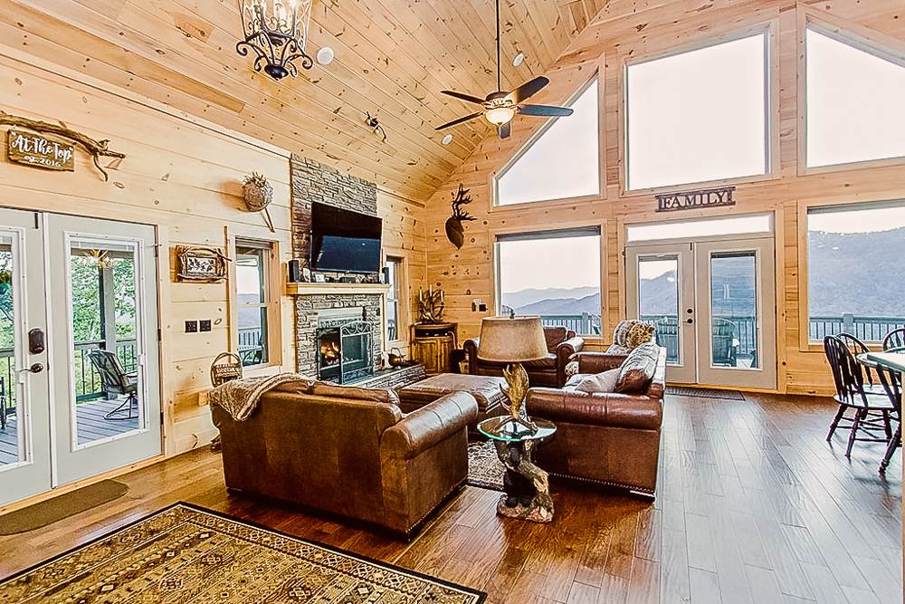 View of living room with lots of seating, wall mounted tv, large picture windows with views of mountains in vacation rentals western North Carolina mountains